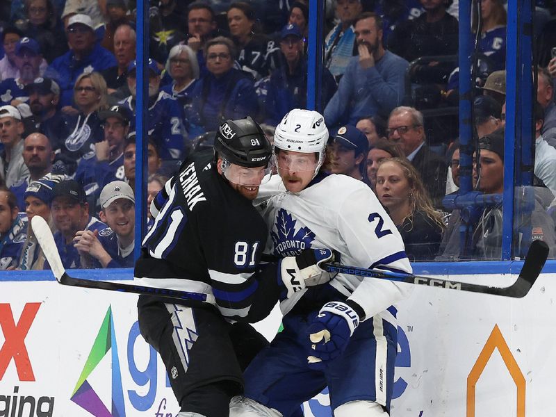 Nov 30, 2024; Tampa, Florida, USA; Tampa Bay Lightning defenseman Erik Cernak (81) and Toronto Maple Leafs defenseman Simon Benoit (2) fight to control the puck during the second period at Amalie Arena. Mandatory Credit: Kim Klement Neitzel-Imagn Images