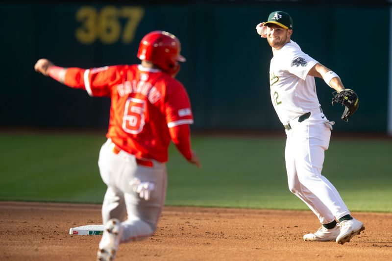 Jul 3, 2024; Oakland, California, USA; Oakland Athletics shortstop Max Schuemann (12) throws over Los Angeles Angels designated hitter Willie Calhoun (5) to complete a double play during the second inning at Oakland-Alameda County Coliseum. Mandatory Credit: D. Ross Cameron-USA TODAY Sports