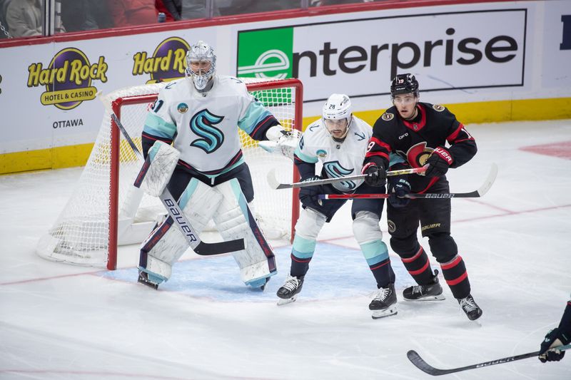 Nov 2, 2024; Ottawa, Ontario, CAN; Ottawa Senators right wing Drake Batherson (19) jockeys for position with Seattle Kraken defenseman Joshua Mahura (28) as they stand in front of goalie Philipp Grubauer (31) in the third period at the Canadian Tire Centre. Mandatory Credit: Marc DesRosiers-Imagn Images