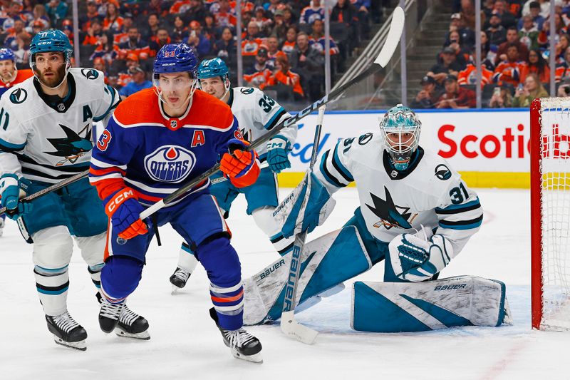 Apr 15, 2024; Edmonton, Alberta, CAN; Edmonton Oilers forward Ryan Nugent-Hopkins (93) and San Jose Sharks goaltender Georgi Romanov (31) look for a loose puck during the third period at Rogers Place. Mandatory Credit: Perry Nelson-USA TODAY Sports