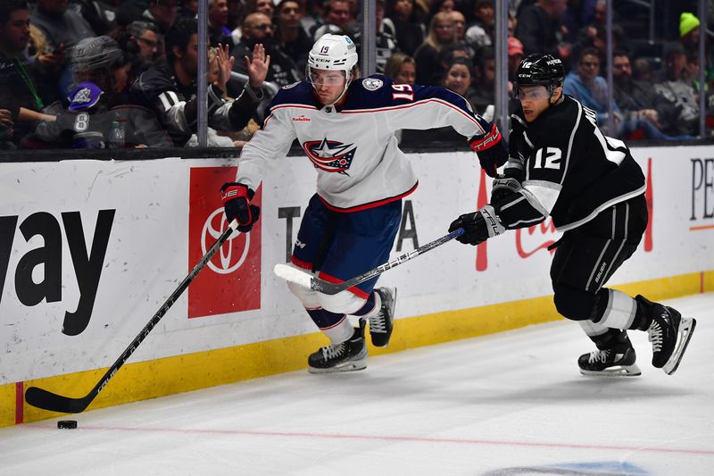 Mar 16, 2023; Los Angeles, California, USA; Columbus Blue Jackets center Liam Foudy (19) moves the puck ahead of Los Angeles Kings left wing Trevor Moore (12) during the third period at Crypto.com Arena. Mandatory Credit: Gary A. Vasquez-USA TODAY Sports