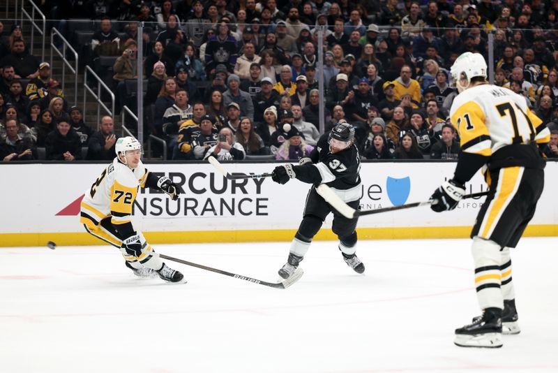 Jan 20, 2025; Los Angeles, California, USA;  Los Angeles Kings left wing Warren Foegele (37) shoots the puck between Pittsburgh Penguins left wing Anthony Beauvillier (72) and center Evgeni Malkin (71) during the second period at Crypto.com Arena. Mandatory Credit: Kiyoshi Mio-Imagn Images