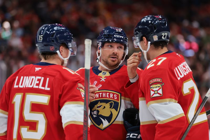Oct 9, 2025; Sunrise, Florida, USA; Florida Panthers center Sam Reinhart (13) speaks to center Anton Lundell (15) and center Eetu Luostarinen (27) against the Philadelphia Flyers during the second period at Amerant Bank Arena. Mandatory Credit: Sam Navarro-Imagn Images