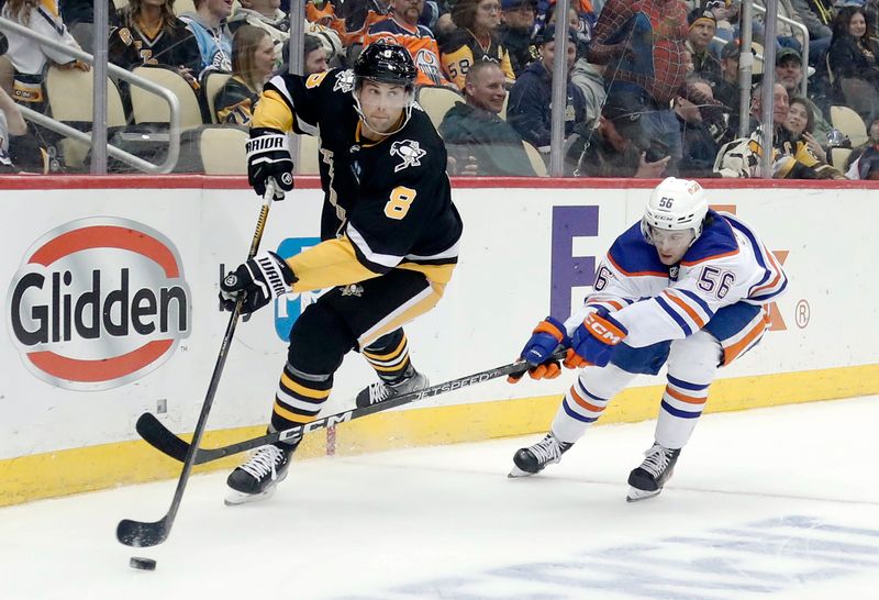 Feb 23, 2023; Pittsburgh, Pennsylvania, USA; Pittsburgh Penguins defenseman Brian Dumoulin (8) moves the puck as Edmonton Oilers right wing Kailer Yamamoto (56) chases during the third period at PPG Paints Arena. Edmonton won 7-2. Mandatory Credit: Charles LeClaire-USA TODAY Sports