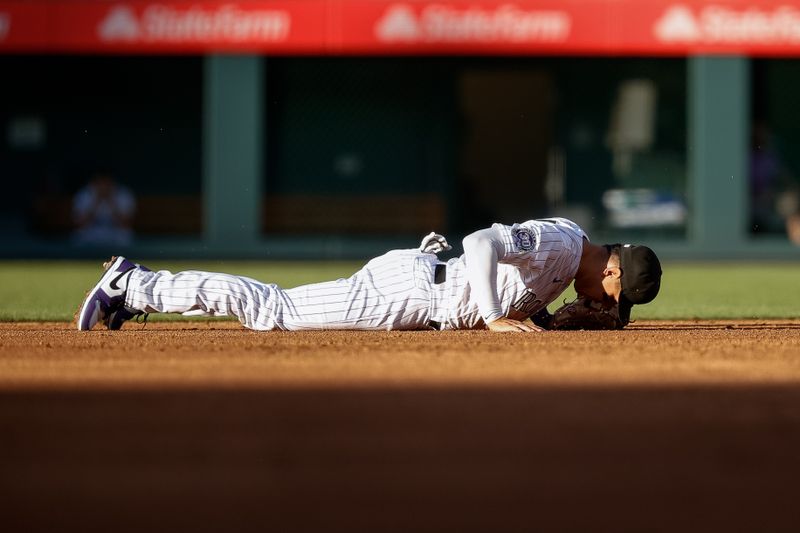 Jul 28, 2023; Denver, Colorado, USA; Colorado Rockies second baseman Alan Trejo (13) lies on the ground after a throwing error in the second inning against the Oakland Athletics at Coors Field. Mandatory Credit: Isaiah J. Downing-USA TODAY Sports