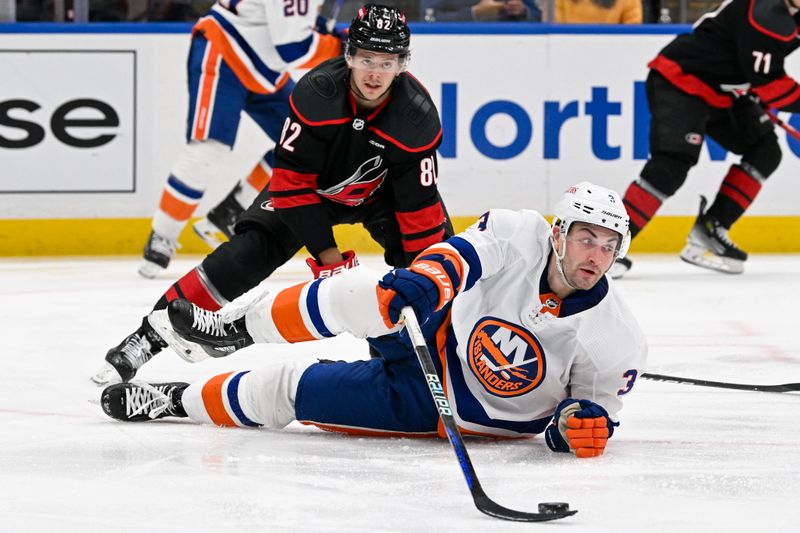 Mar 19, 2024; Elmont, New York, USA; New York Islanders defenseman Adam Pelech (3) and Carolina Hurricanes center Jesperi Kotkaniemi (82) battle for the puck during the third period at UBS Arena. Mandatory Credit: Dennis Schneidler-USA TODAY Sports