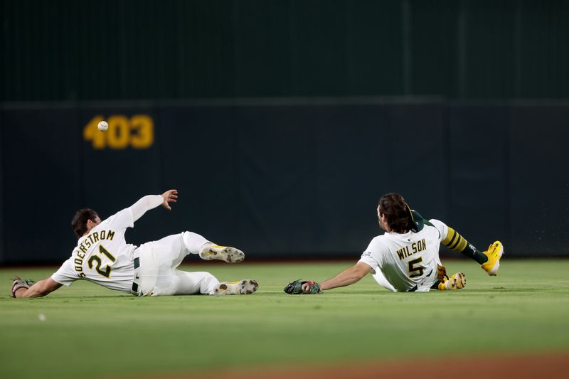 Sep 27, 2025; West Sacramento, California, USA; Athletics left fielder Tyler Soderstrom (21) and shortstop Jacob Wilson (5) slide to avoid a collision while chasing a fly ball against the Kansas City Royals during the fifth inning at Sutter Health Park. Mandatory Credit: Dennis Lee-Imagn Images