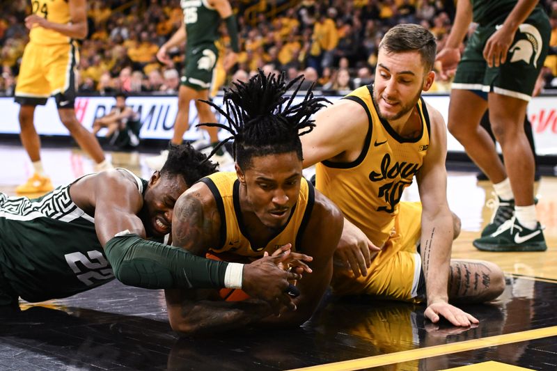 Feb 25, 2023; Iowa City, Iowa, USA; Michigan State Spartans center Mady Sissoko (22) and Iowa Hawkeyes guard Ahron Ulis (center) and guard Connor McCaffery (right) battle for a loose ball during the first half at Carver-Hawkeye Arena. Mandatory Credit: Jeffrey Becker-USA TODAY Sports