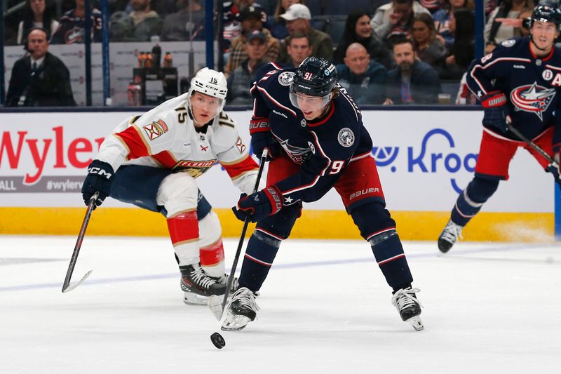 Oct 15, 2024; Columbus, Ohio, USA; Columbus Blue Jackets center Kent Johnson (91) passes the puck as Florida Panthers center Anton Lundell (15) trails the play during the second period at Nationwide Arena. Mandatory Credit: Russell LaBounty-Imagn Images