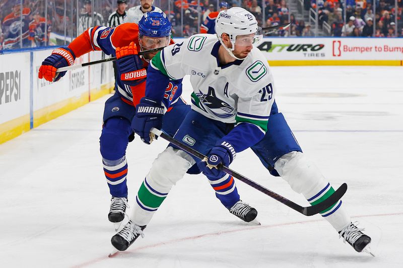 Sep 28, 2025; Edmonton, Alberta, CAN; Vancouver Canucks defensemen Marcus Pettersson (29) and Edmonton Oilers forward Leon Draisaitl (29) chase a loose puck during the first period at Rogers Place. Mandatory Credit: Perry Nelson-Imagn Images