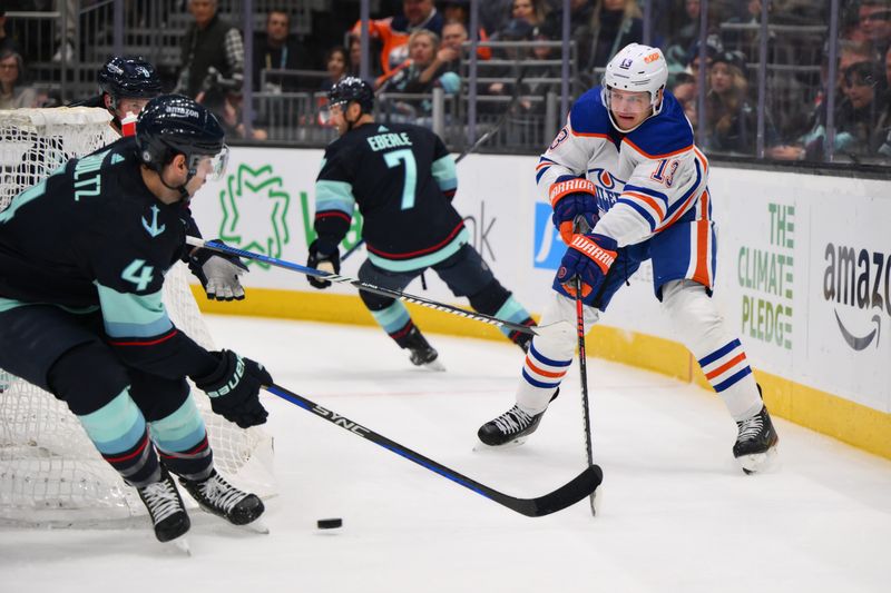 Mar 2, 2024; Seattle, Washington, USA; Edmonton Oilers center Mattias Janmark (13) passes the puck while defended by Seattle Kraken defenseman Justin Schultz (4) during the third period at Climate Pledge Arena. Mandatory Credit: Steven Bisig-USA TODAY Sports