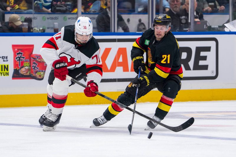 Oct 30, 2024; Vancouver, British Columbia, CAN; Vancouver Canucks forward Nils Hoglander (21) stick checks New Jersey Devils defenseman Jonas Siegenthaler (71) during the second period at Rogers Arena. Mandatory Credit: Bob Frid-Imagn Images