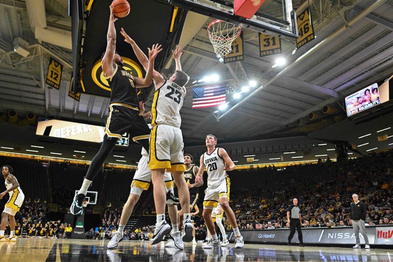 Dec 20, 2023; Iowa City, Iowa, USA; UMBC Retrievers center Max Lorca-Lloyd (5) shoots the ball over Iowa Hawkeyes forward Ben Krikke (23) and forward Payton Sandfort (20) defend during the first half at Carver-Hawkeye Arena. Mandatory Credit: Jeffrey Becker-USA TODAY Sports