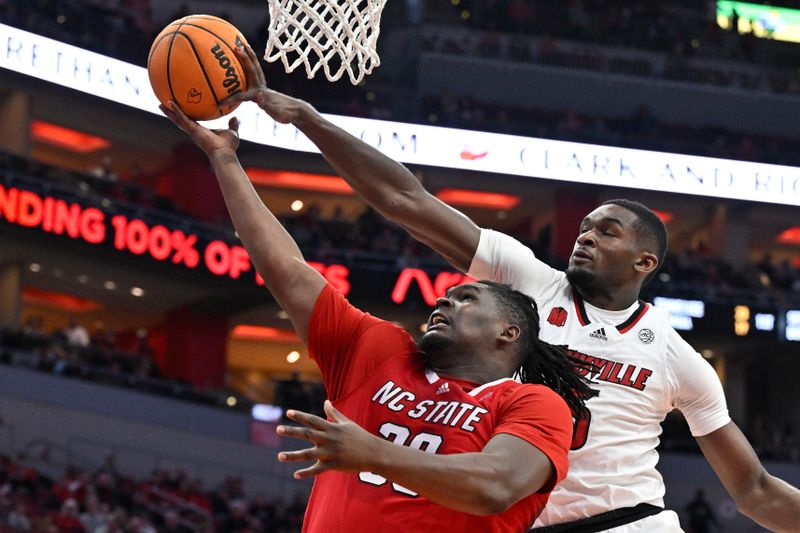 Jan 13, 2024; Louisville, Kentucky, USA;  Louisville Cardinals forward Brandon Huntley-Hatfield (5) blocks the shot of North Carolina State Wolfpack forward DJ Burns Jr. (30) during the first half at KFC Yum! Center.  Mandatory Credit: Jamie Rhodes-USA TODAY Sports