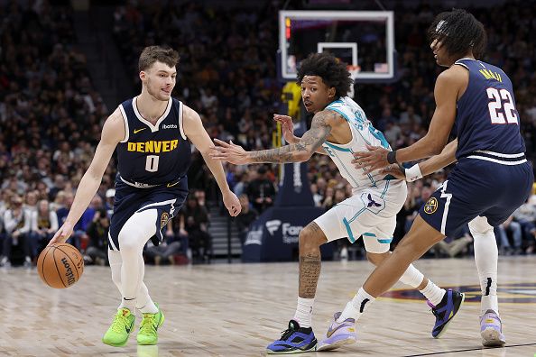 DENVER, COLORADO - JANUARY 01: Christian Braun #0 of the Denver Nuggets drives against Nick Smith Jr. #8 of the Charlotte Hornets off a pick by Zeke Nnaji #22 in the first quarter at Ball Arena on January 01, 2024 in Denver, Colorado. NOTE TO USER: User expressly acknowledges and agrees that, by downloading and or using this photograph, User is consenting to the terms and conditions of the Getty Images License Agreement.   (Photo by Matthew Stockman/Getty Images)