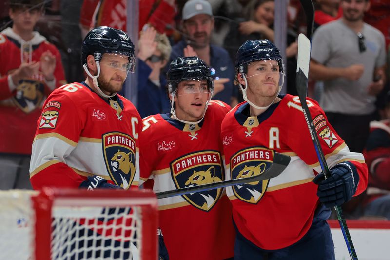 Nov 30, 2024; Sunrise, Florida, USA; Florida Panthers right wing Mackie Samoskevich (center) celebrates with center Aleksander Barkov (left) and left wing Matthew Tkachuk (right) after scoring against the Carolina Hurricanes during the second period at Amerant Bank Arena. Mandatory Credit: Sam Navarro-Imagn Images