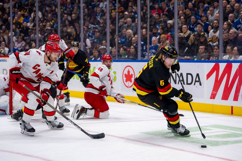 Oct 28, 2024; Vancouver, British Columbia, CAN; Carolina Hurricanes defenseman Jaccob Slavin (74) defends against Vancouver Canucks forward Brock Boeser (6) during the first period at Rogers Arena. Mandatory Credit: Bob Frid-Imagn Images