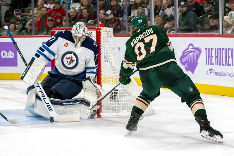 Nov 25, 2024; Saint Paul, Minnesota, USA;  Minnesota Wild forward Kirill Kaprizov (97) sends a pass through the crease of Winnipeg Jets goalie Connor Hellebuyck (37) during the second period at Xcel Energy Center. Mandatory Credit: Nick Wosika-Imagn Images