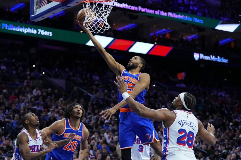 PHILADELPHIA, PENNSYLVANIA - JANUARY 15: Mikal Bridges #25 of the New York Knicks lays up a shot against Guerschon Yabusele #28 of the Philadelphia 76ers in the second half at the Wells Fargo Center on January 15, 2025 in Philadelphia, Pennsylvania. The Knicks defeated the 76ers 125-119 in overtime. NOTE TO USER: User expressly acknowledges and agrees that, by downloading and/or using this photograph, user is consenting to the terms and conditions of the Getty Images License Agreement. (Photo by Mitchell Leff/Getty Images)