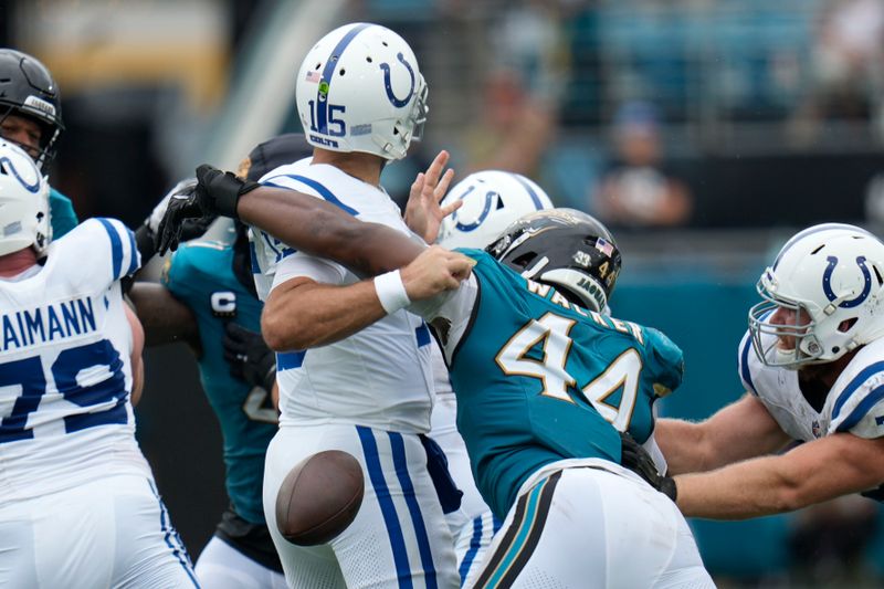 Indianapolis Colts quarterback Joe Flacco (15) fumbles as he is hit by Jacksonville Jaguars' Travon Walker (44) during the first half of an NFL football game, Sunday, Oct. 6, 2024, in Jacksonville, Fla. (AP Photo/John Raoux)