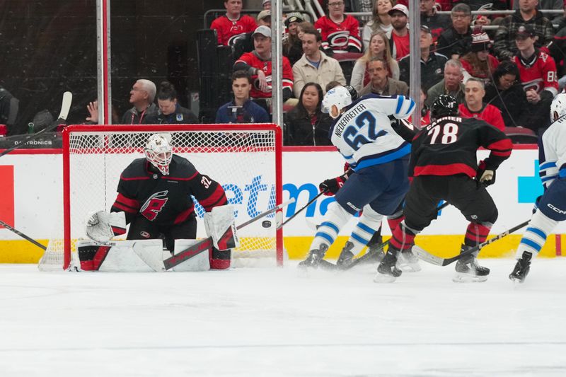 Nov 28, 2025; Raleigh, North Carolina, USA;  Carolina Hurricanes goaltender Brandon Bussi (32) watches Winnipeg Jets right wing Nino Niederreiter (62) shot during the third period at Lenovo Center. Mandatory Credit: James Guillory-Imagn Images