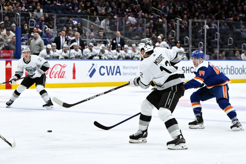 Dec 9, 2023; Elmont, New York, USA; Los Angeles Kings left wing Trevor Moore (12) passes the puck as New York Islanders center Jean-Gabriel Pageau (44) defends during the first period at UBS Arena. Mandatory Credit: John Jones-USA TODAY Sports