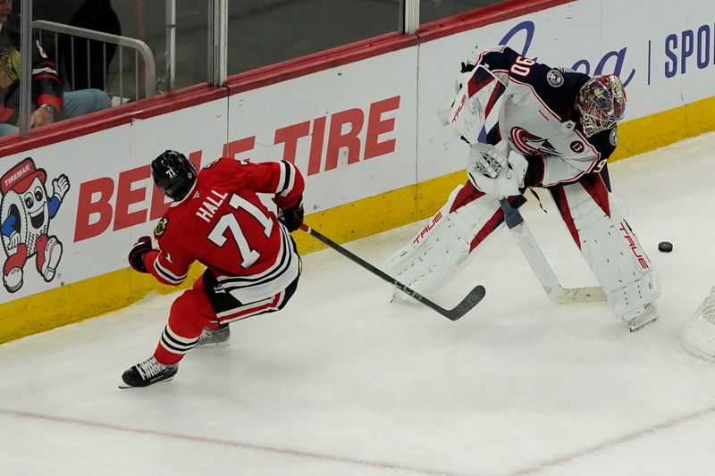 Dec 1, 2024; Chicago, Illinois, USA; Chicago Blackhawks left wing Taylor Hall (71) and Columbus Blue Jackets goaltender Elvis Merzlikins (90) go for the puck during the third period at United Center. Mandatory Credit: David Banks-Imagn Images