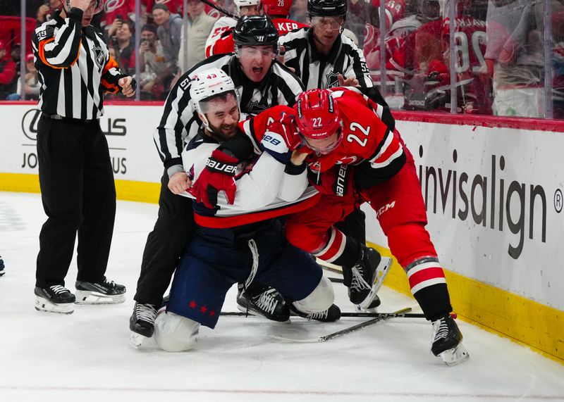 Apr 2, 2025; Raleigh, North Carolina, USA;  Carolina Hurricanes center Logan Stankoven (22) and Washington Capitals right wing Tom Wilson (43) battle during the third period at Lenovo Center. Mandatory Credit: James Guillory-Imagn Images
