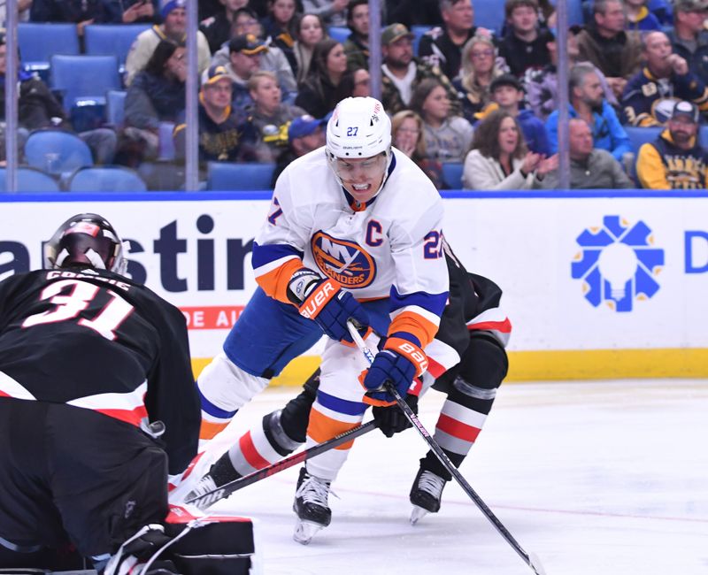 Oct 21, 2023; Buffalo, New York, USA; New York Islanders left wing Anders Lee (27) tries to take a shot on goal as Buffalo Sabres goaltender Eric Comrie (31) defends in the third period at KeyBank Center. Mandatory Credit: Mark Konezny-USA TODAY Sports