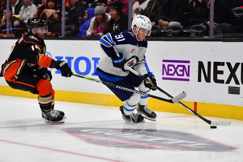 Jan 5, 2024; Anaheim, California, USA; Winnipeg Jets center Cole Perfetti (91) moves the puck ahead of Anaheim Ducks center Adam Henrique (14) during the third period at Honda Center. Mandatory Credit: Gary A. Vasquez-USA TODAY Sports