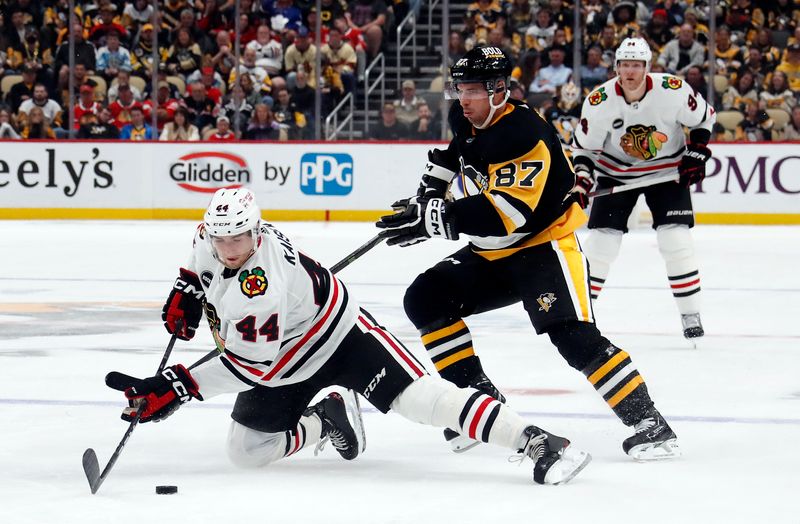 Oct 10, 2023; Pittsburgh, Pennsylvania, USA; Chicago Blackhawks defenseman Wyatt Kaiser (44) clears the puck ahead of Pittsburgh Penguins center Sidney Crosby (87) during the third period at the PPG Paints Arena. Chicago won 4-2. Mandatory Credit: Charles LeClaire-USA TODAY Sports