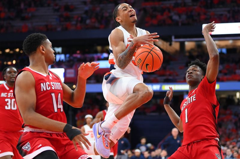 Feb 14, 2023; Syracuse, New York, USA; Syracuse Orange guard Judah Mintz (3) loses control of the ball on a drive to the basket between North Carolina State Wolfpack guard Casey Morsell (14) and guard Jarkel Joiner (1) during the first half at the JMA Wireless Dome. Mandatory Credit: Rich Barnes-USA TODAY Sports