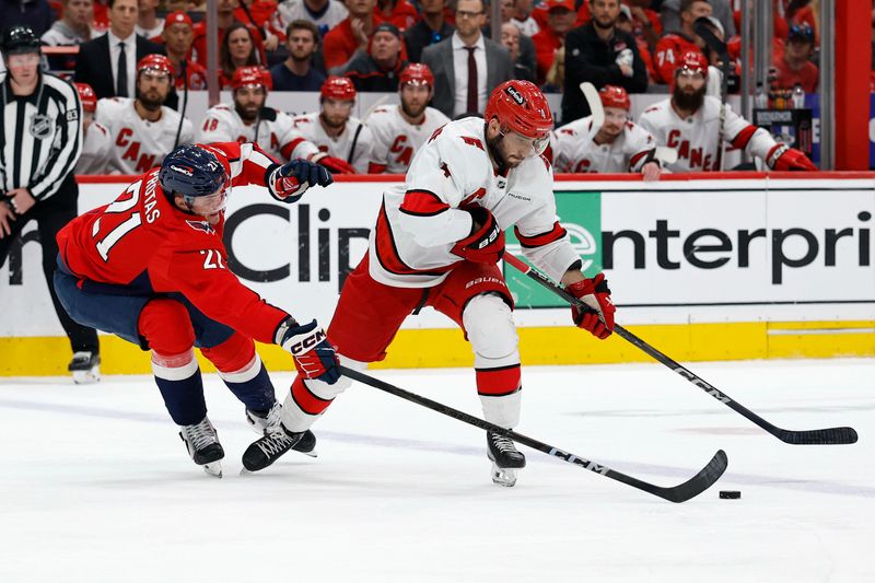 May 15, 2025; Washington, District of Columbia, USA; Carolina Hurricanes defenseman Shayne Gostisbehere (4) skates with the puck as Washington Capitals center Aliaksei Protas (21) defends in the second period in game five of the second round of the 2025 Stanley Cup Playoffs at Capital One Arena. Mandatory Credit: Geoff Burke-Imagn Images