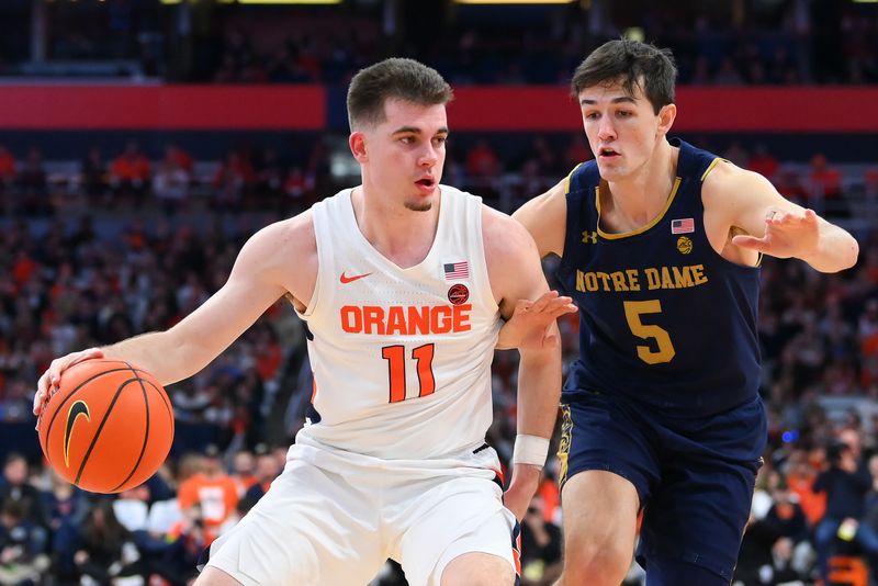 Jan 14, 2023; Syracuse, New York, USA; Syracuse Orange guard Joseph Girard III (11) drives to the basket against the defense of Notre Dame Fighting Irish guard Cormac Ryan (5) during the first half at the JMA Wireless Dome. Mandatory Credit: Rich Barnes-USA TODAY Sports