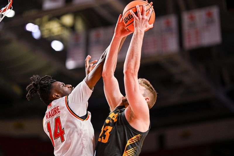 Feb 14, 2024; College Park, Maryland, USA;  Maryland Terrapins forward Mady Traore (14) blocks Iowa Hawkeyes forward Ben Krikke (23) fist half shot at Xfinity Center. Mandatory Credit: Tommy Gilligan-USA TODAY Sports