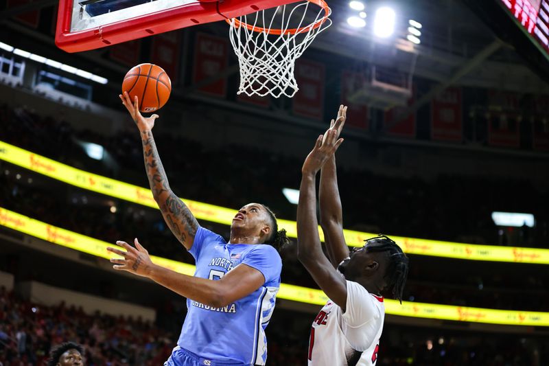 Feb 19, 2023; Raleigh, North Carolina, USA;  North Carolina Tar Heels forward Armando Bacot (5) looks to make a layup against North Carolina State Wolfpack forward Ebenezer Dowuona (21) during the second half of the game at PNC Arena. Mandatory Credit: Jaylynn Nash-USA TODAY Sports