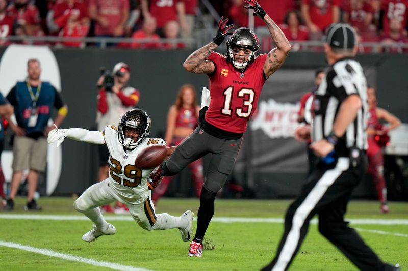 Tampa Bay Buccaneers wide receiver Mike Evans (13) can't hold onto a pass as he is interfered with by New Orleans Saints cornerback Paulson Adebo (29) in the second half of an NFL football game in Tampa, Fla., Monday, Dec. 5, 2022. The Buccaneers won 17-16. (AP Photo/Chris O'Meara)