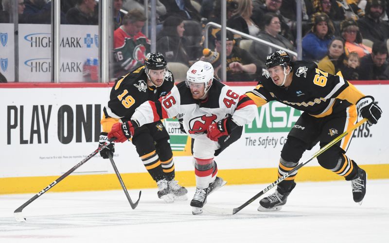 Nov 16, 2023; Pittsburgh, Pennsylvania, USA; New Jersey Devils center Max Willman (46) moves the puck between right wing Reilly Smith (19) and right wing Rickard Rakell (67) during the second period at PPG Paints Arena. Mandatory Credit: Philip G. Pavely-USA TODAY Sports