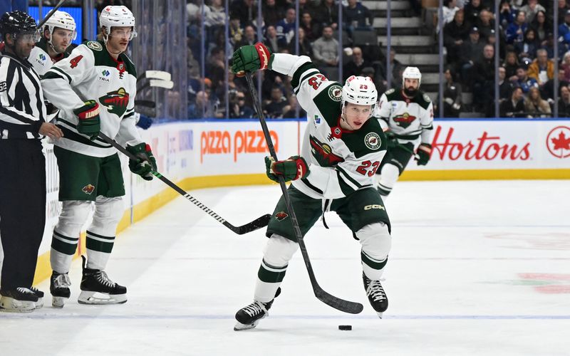 Jan 29, 2025; Toronto, Ontario, CAN; Minnesota Wild forward Marco Rossi (23) plays a back pass to defenseman Jon Merrill (4) in the second period against the Toronto Maple Leafs at Scotiabank Arena. Mandatory Credit: Dan Hamilton-Imagn Images