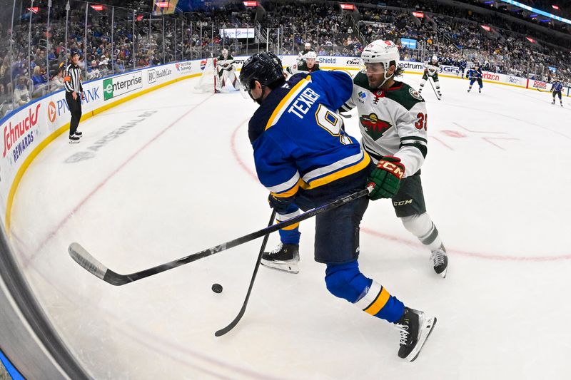 Nov 19, 2024; St. Louis, Missouri, USA;  St. Louis Blues center Alexandre Texier (9) controls the puck as Minnesota Wild right wing Ryan Hartman (38) defends during the second period at Enterprise Center. Mandatory Credit: Jeff Curry-Imagn Images