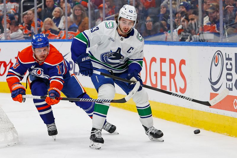 Jan 23, 2025; Edmonton, Alberta, CAN; Vancouver Canucks defensemen Quinn Hughes (43) clears the puck in front of Edmonton Oilers Edmonton Oilers forward Mattias Janmark (13) during the third period at Rogers Place. Mandatory Credit: Perry Nelson-Imagn Images