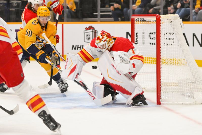 Dec 2, 2025; Nashville, Tennessee, USA;  Calgary Flames goaltender Devin Cooley (1) blocks the shot of Nashville Predators left wing Michael Bunting (58) during the first period at Bridgestone Arena. Mandatory Credit: Steve Roberts-Imagn Images