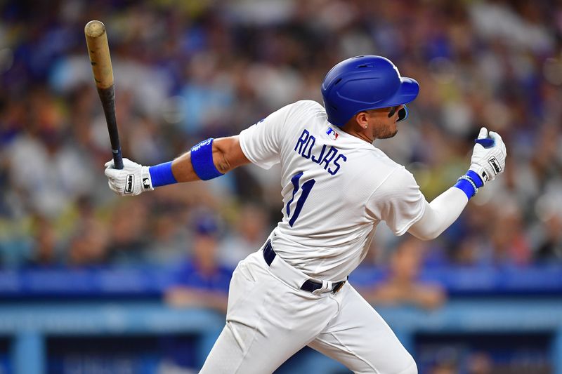 Aug 15, 2023; Los Angeles, California, USA; Los Angeles Dodgers shortstop Miguel Rojas (11) hits a sacrifice RBI against the Milwaukee Brewers during the fifth inning at Dodger Stadium. Mandatory Credit: Gary A. Vasquez-USA TODAY Sports