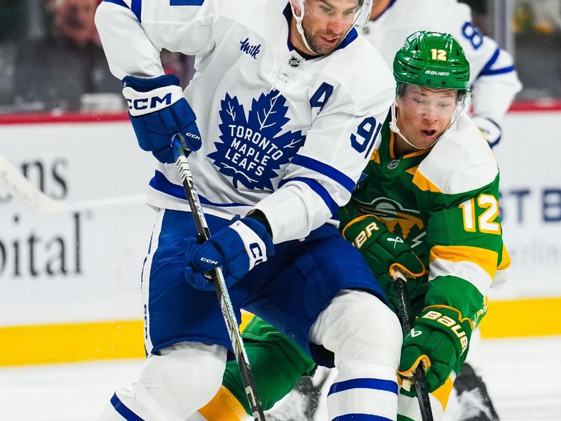 Nov 3, 2024; Saint Paul, Minnesota, USA; Toronto Maple Leafs center John Tavares (91) protects the puck from Minnesota Wild left wing Matt Boldy (12) during the first period at Xcel Energy Center. Mandatory Credit: Brace Hemmelgarn-Imagn Images