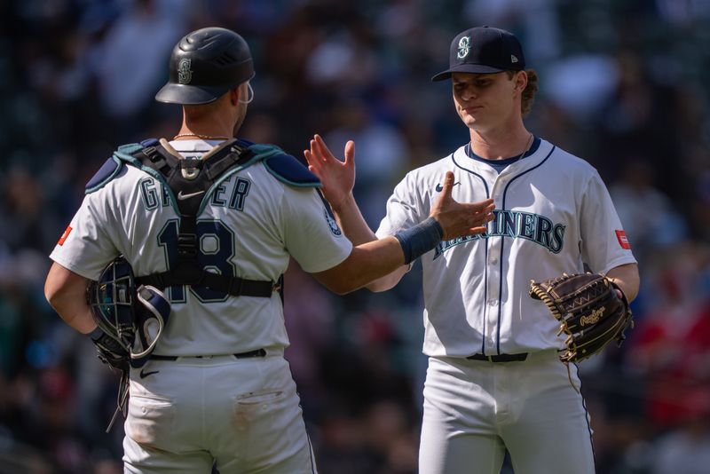 Apr 30, 2025; Seattle, Washington, USA;  Seattle Mariners relief pitcher Troy Taylor (59), right, and catcher Mitch Garver (18) celebrate after a game against the Los Angeles Angels at T-Mobile Park. Mandatory Credit: Stephen Brashear-Imagn Images