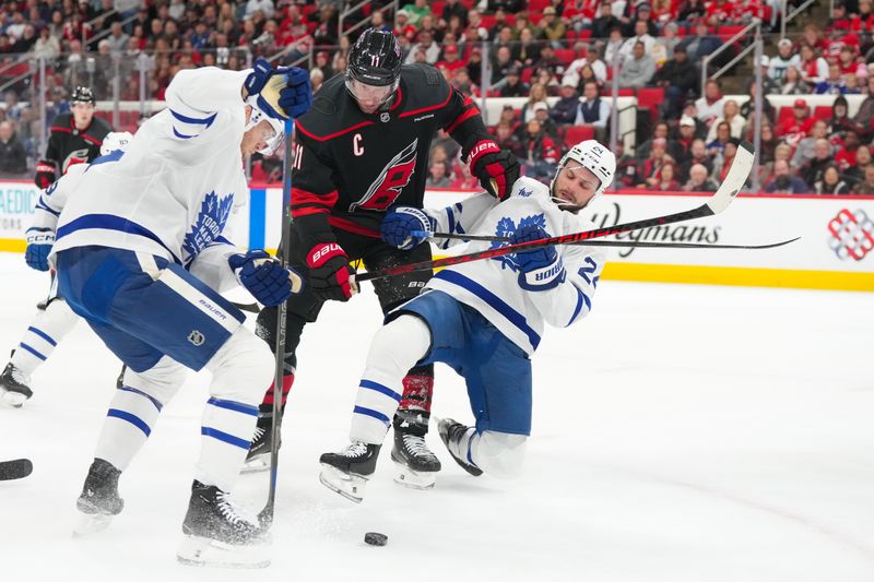 Dec 4, 2025; Raleigh, North Carolina, USA; Carolina Hurricanes center Jordan Staal (11) and Toronto Maple Leafs center Scott Laughton (24) battle over the puck during the first period at Lenovo Center. Mandatory Credit: James Guillory-Imagn Images