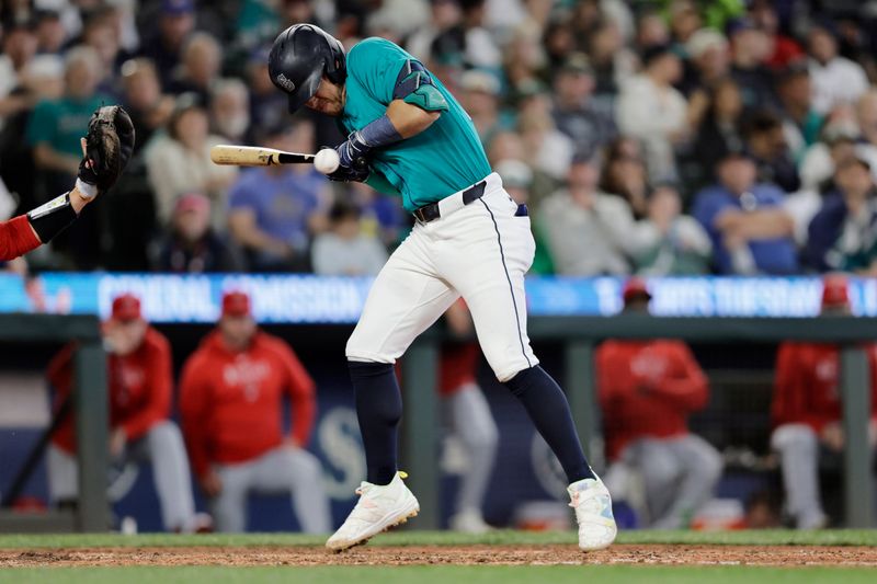 Jun 1, 2024; Seattle, Washington, USA;  Seattle Mariners third baseman Dylan Moore (25) is hit by a pitch against the Los Angeles Angels during the sixth inning at T-Mobile Park. Mandatory Credit: John Froschauer-USA TODAY Sports