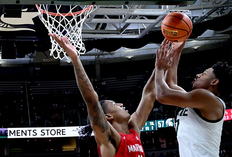 Feb 7, 2023; East Lansing, Michigan, USA; Michigan State Spartans guard A.J. Hoggard (11) puts in a shot past Maryland Terrapins forward Julian Reese (10) in the second half at Jack Breslin Student Events Center. Mandatory Credit: Dale Young-USA TODAY Sports