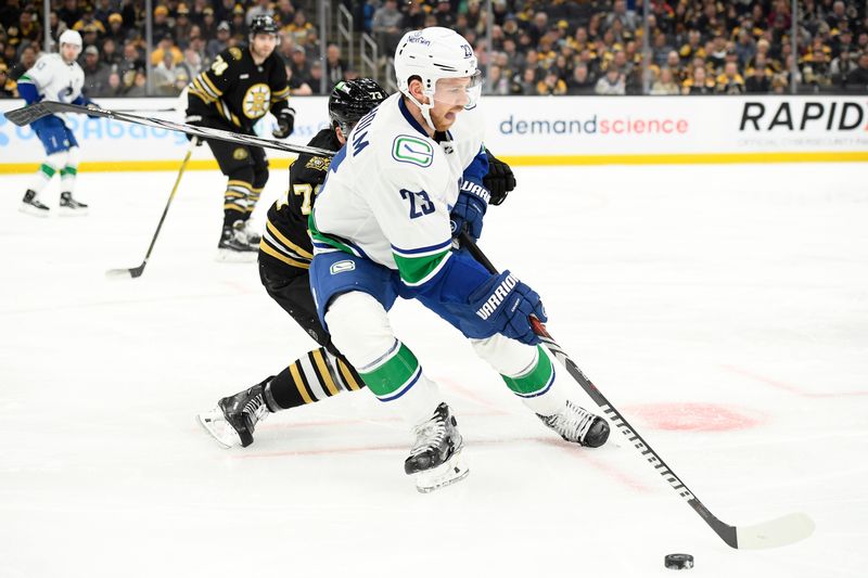 Feb 8, 2024; Boston, Massachusetts, USA; Vancouver Canucks center Elias Lindholm (23) controls the puck from Boston Bruins defenseman Charlie McAvoy (73) during the second period at TD Garden. Mandatory Credit: Bob DeChiara-USA TODAY Sports