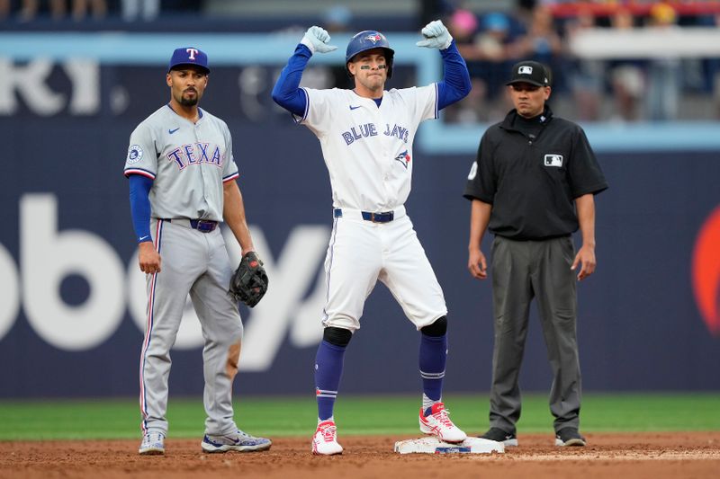 Jul 26, 2024; Toronto, Ontario, CAN; Toronto Blue Jays third baseman Ernie Clement (28) celebrates his one run double as Texas Rangers second baseman Marcus Semien (2) looks on during the first inning at Rogers Centre. Mandatory Credit: John E. Sokolowski-USA TODAY Sports